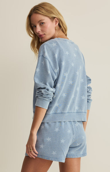 Woman wearing a light blue star-patterned loungewear set on a beige background