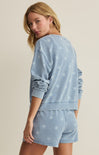Woman wearing a light blue star-patterned loungewear set on a beige background