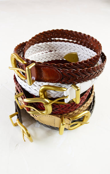 Stack of woven belts with gold buckles on a white background