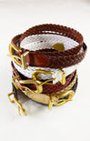 Stack of woven belts with gold buckles on a white background