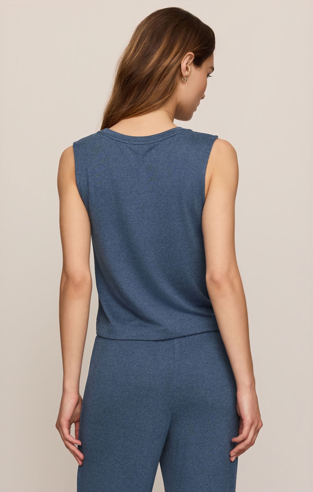A woman shown from the back wearing a sleeveless heathered blue top and matching blue pants against a plain light beige studio background.