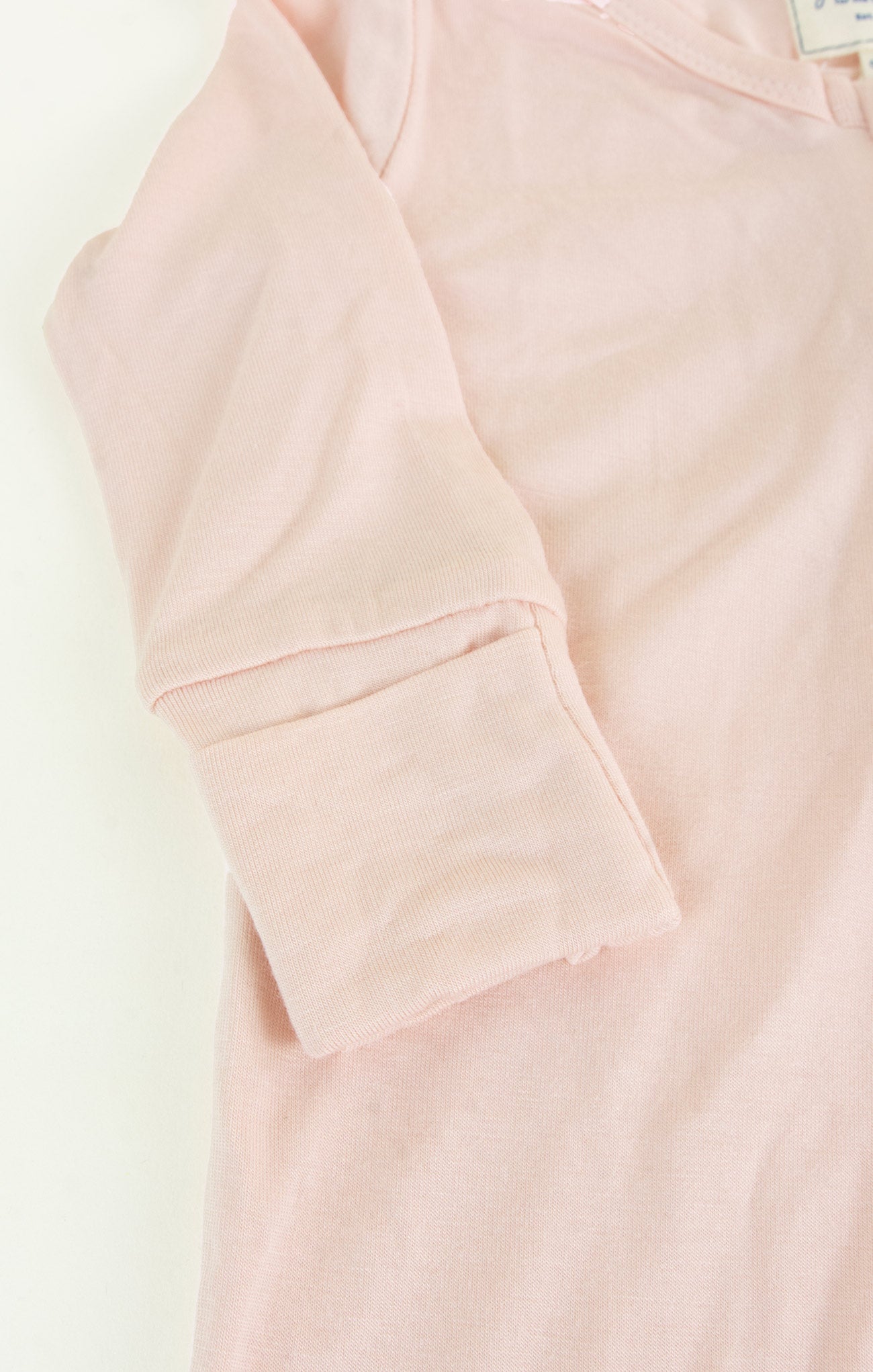 Close-up of a light pink hoodie with a pocket on a white background