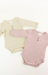 Two baby bodysuits, one beige and one pink, on a white background.
