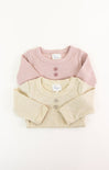Two baby sweaters, one pink and one beige, on a white background