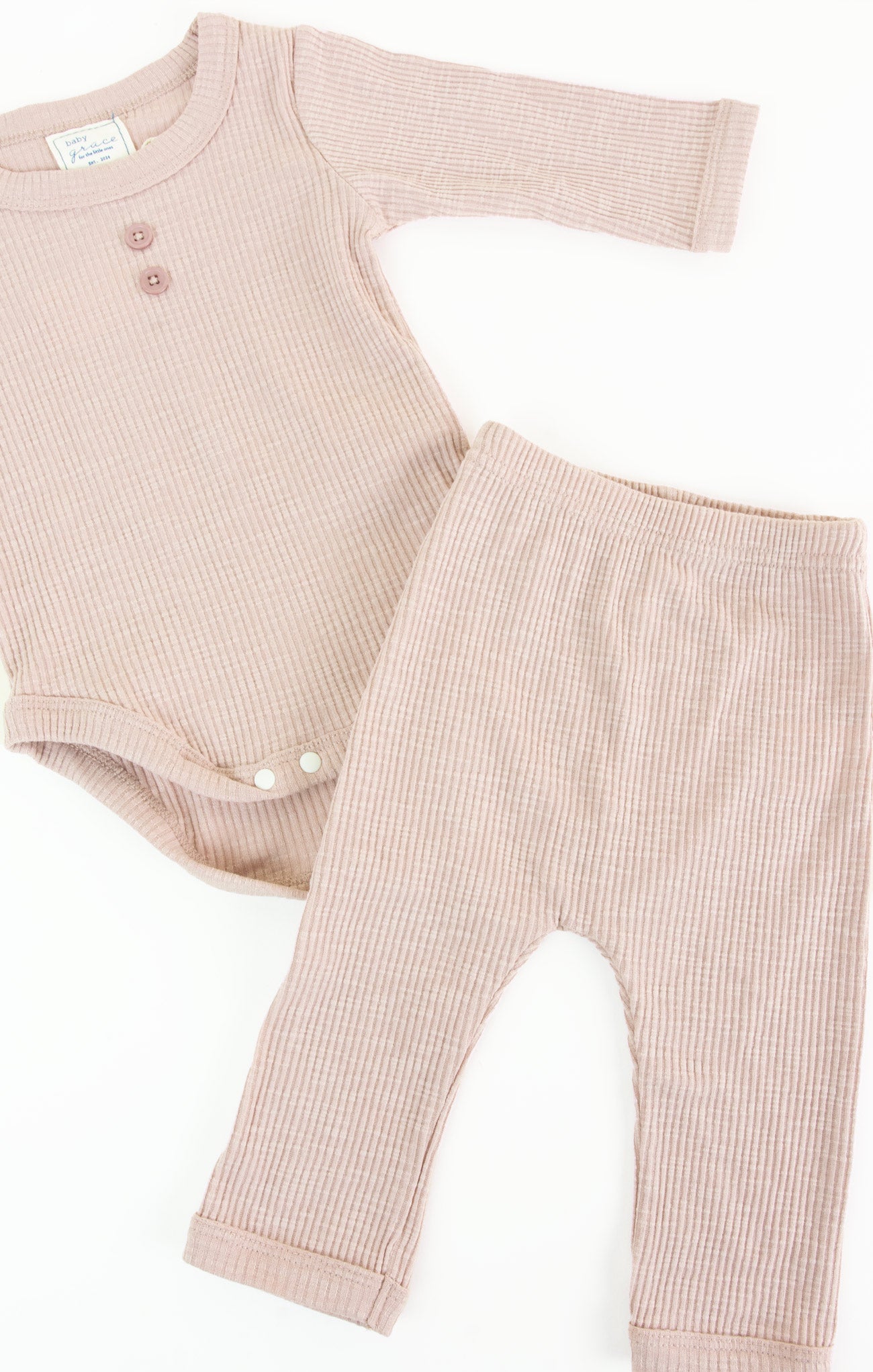 Baby romper and pants set in ribbed pink fabric on a white background
