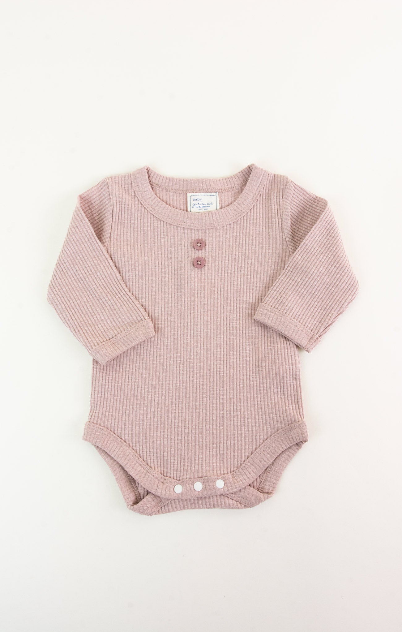 Pink ribbed baby onesie on a white background