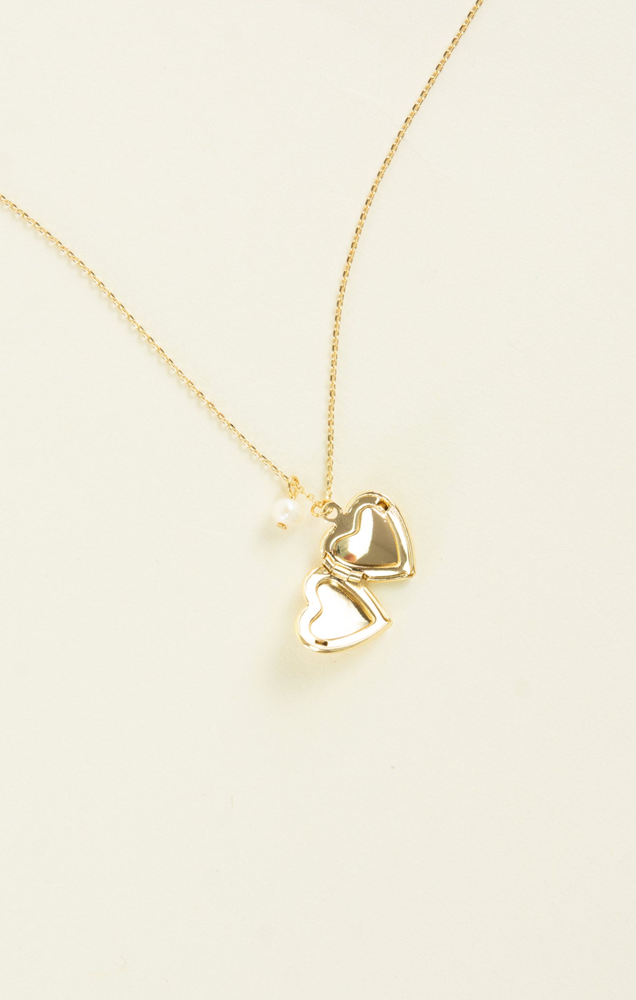 Gold necklace with heart pendants on a beige background