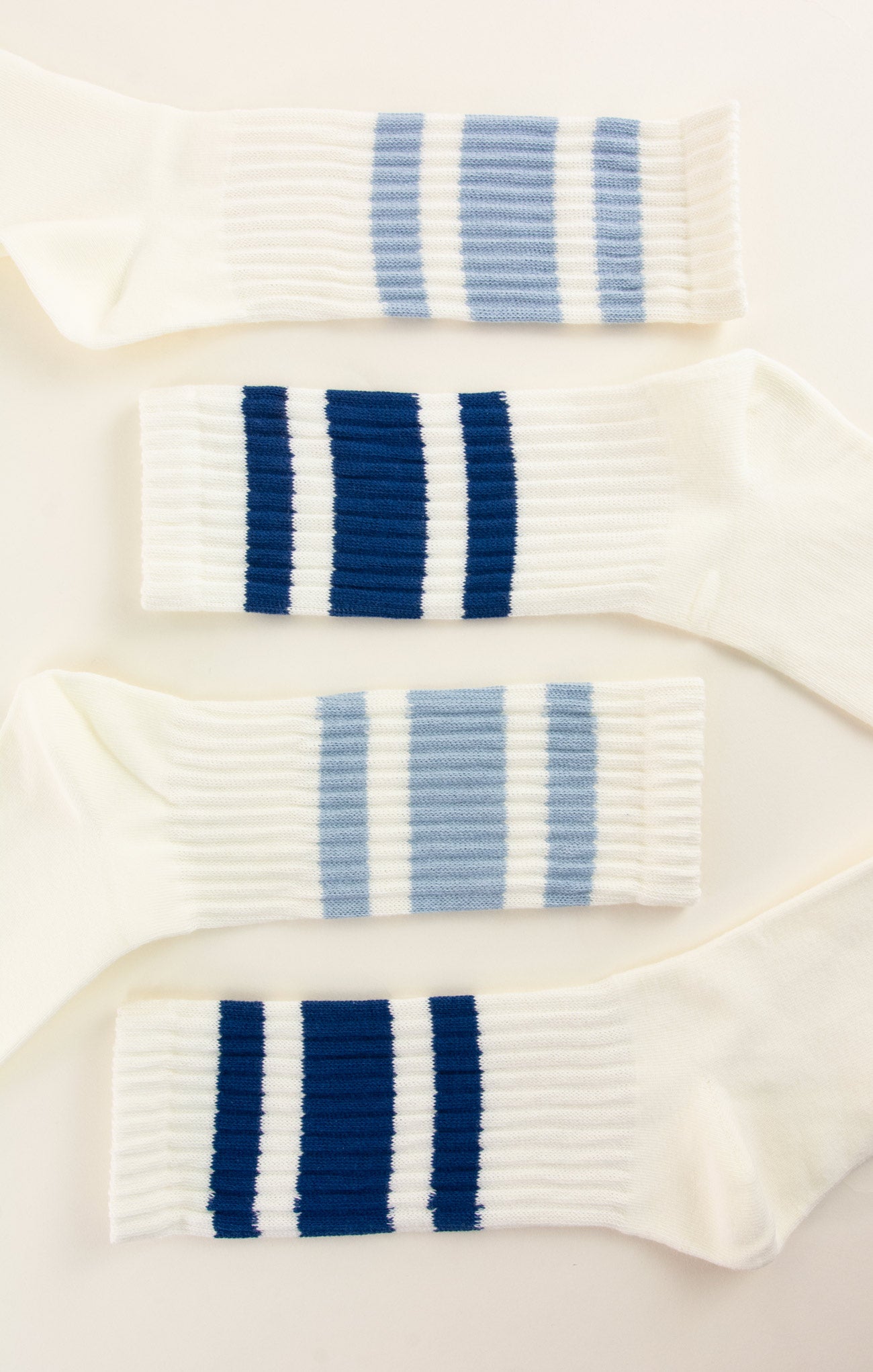 Three pairs of socks with blue and white stripes on a light background