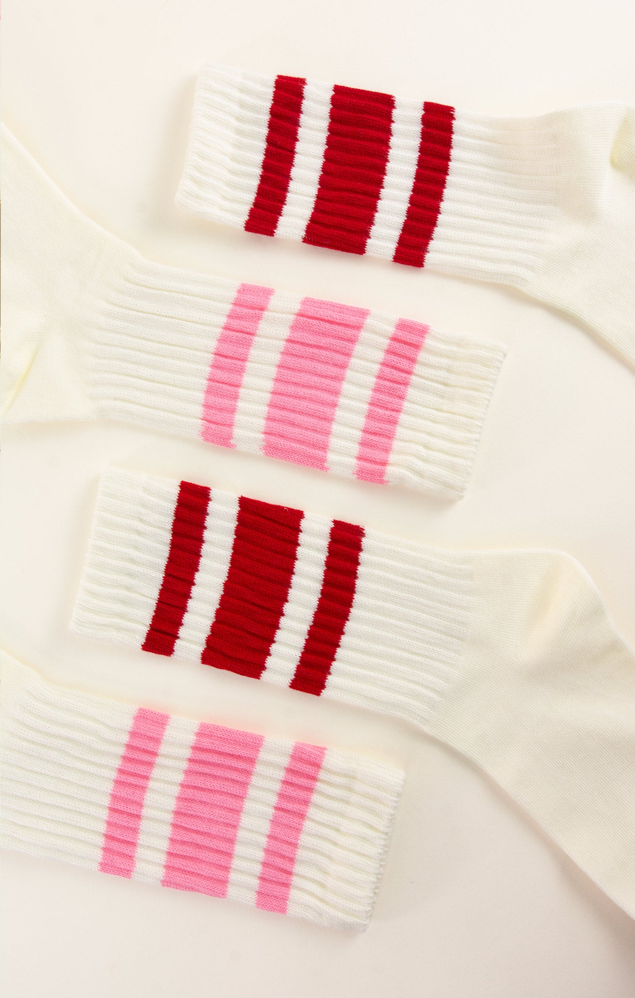 Close-up of a white sweater with red and pink striped patterns on a white background