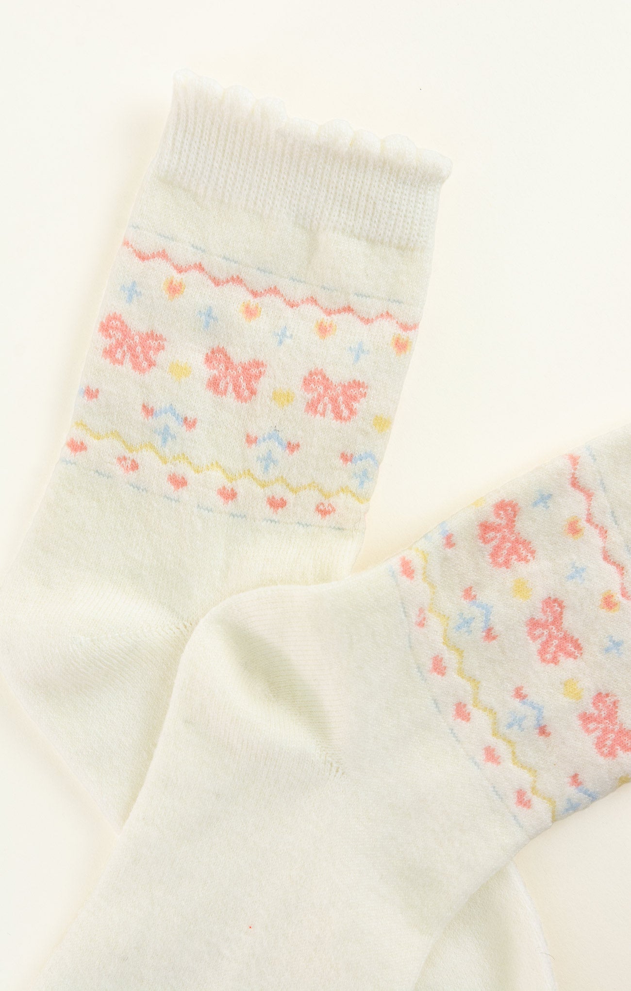 Pair of cream-colored socks with floral patterns on a white background