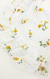 Floral patterned fabric with yellow flowers and green leaves on a white background