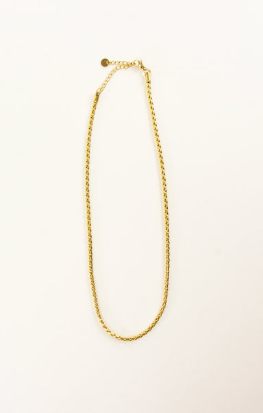 Gold chain necklace on a light beige background
