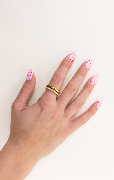 Hand with pink nail polish and a gold ring on a white background