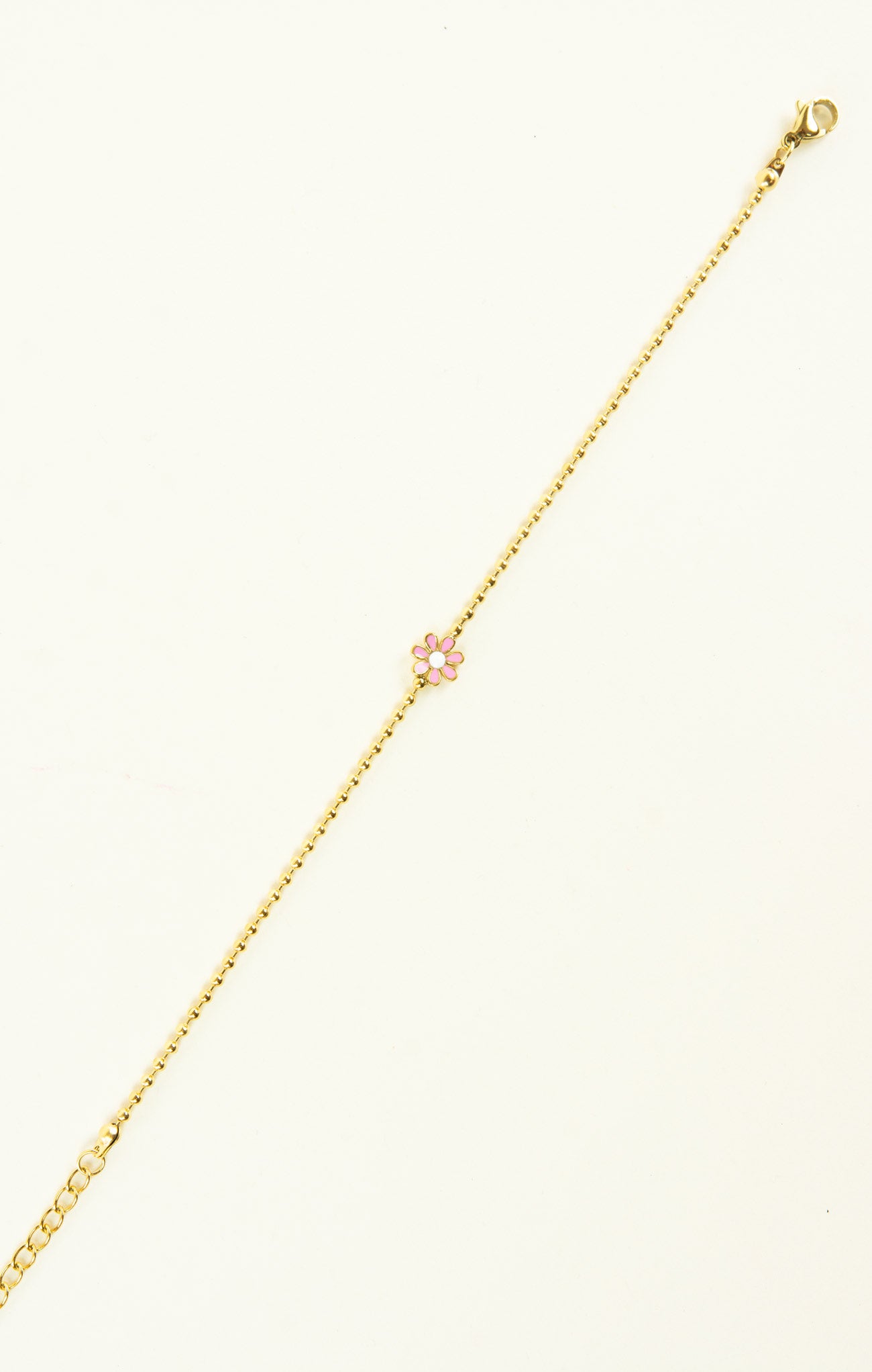 Gold bracelet with a pink heart charm on a white background