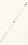 Gold bracelet with a pink heart charm on a white background