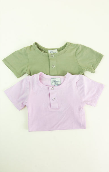 Two short-sleeve shirts, one green and one pink, on a white background.