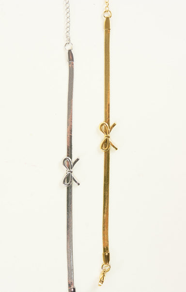 Three gold and silver necklaces with bow accents on a white background