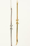 Three gold and silver necklaces with bow accents on a white background