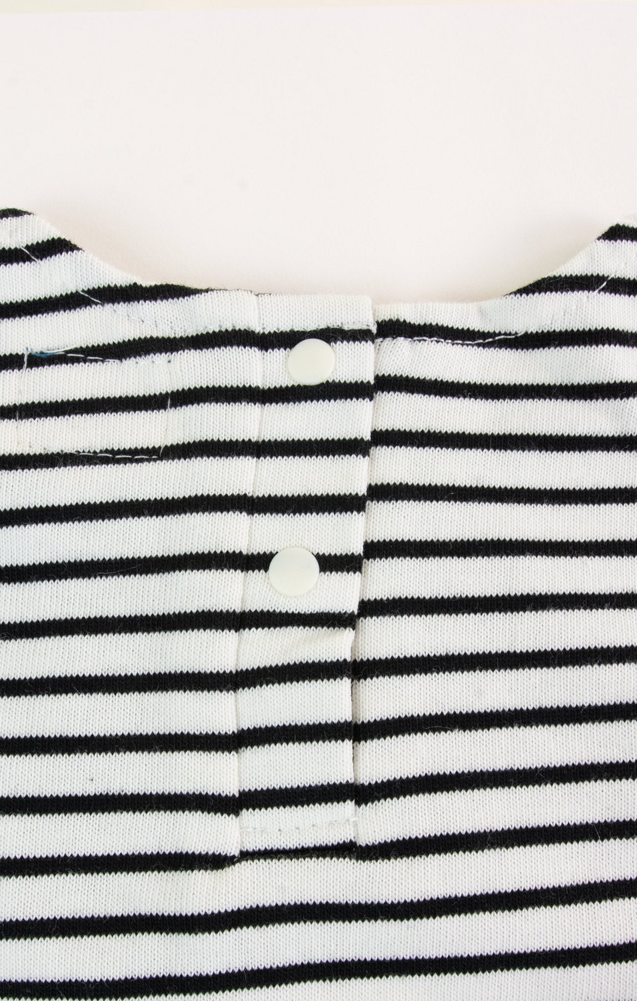 Close-up of a black and white striped garment with buttons on a white background