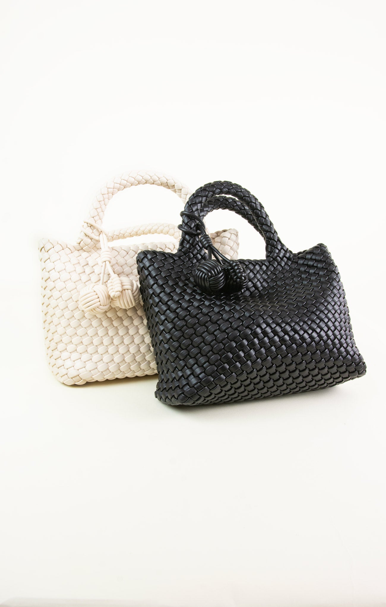Two woven handbags, one black and one white, on a white background