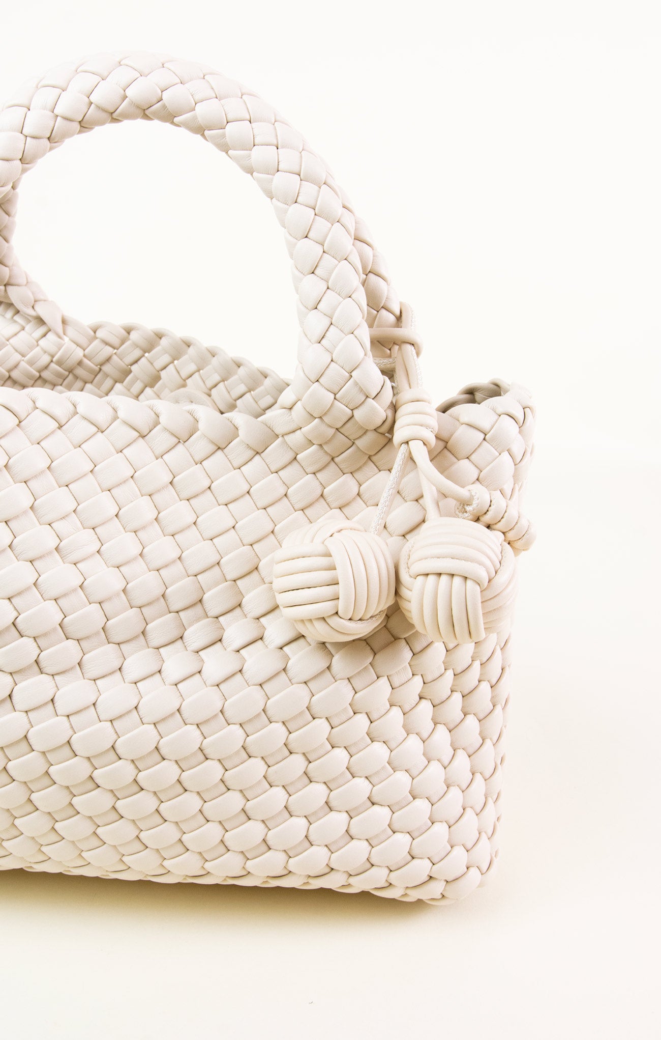 White woven handbag with tassel on a white background