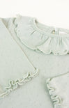 Light green baby outfit with ruffled details on a white background