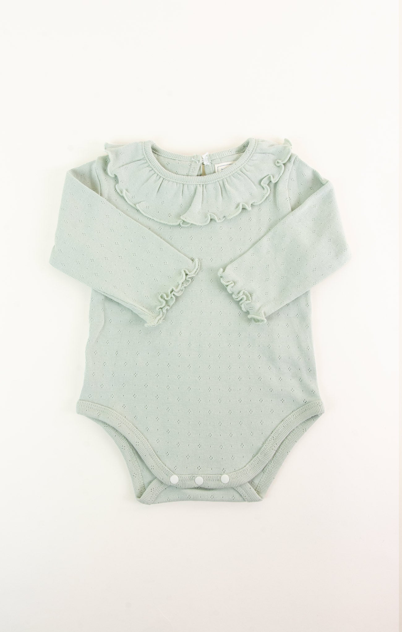 Light green baby romper with ruffled collar on a white background