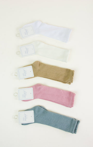 Set of four baby socks in white, beige, pink, and blue on a light background