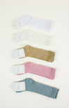 Set of four baby socks in white, beige, pink, and blue on a light background