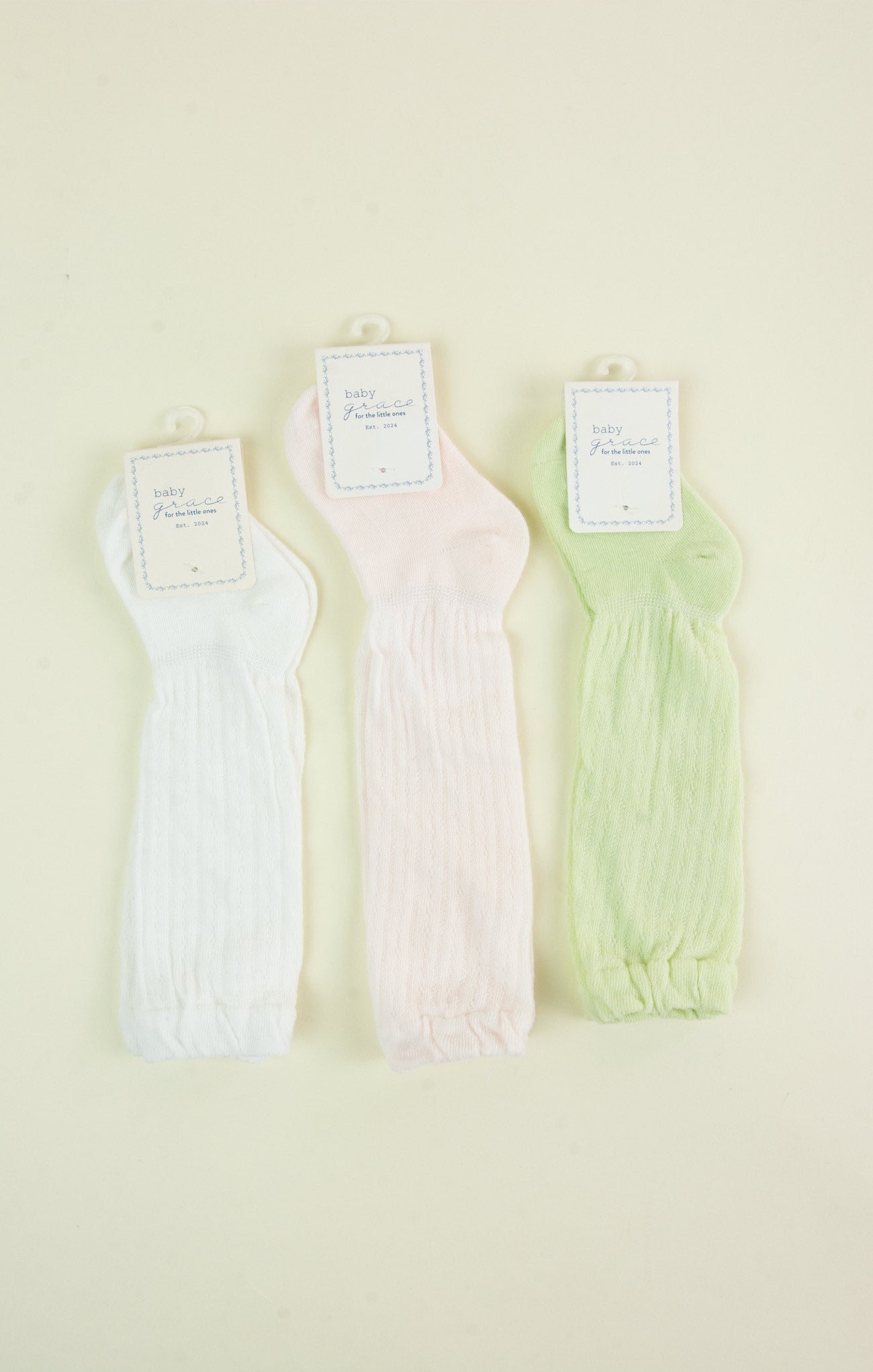 Three pairs of pastel-colored ribbed tank tops on a light beige background