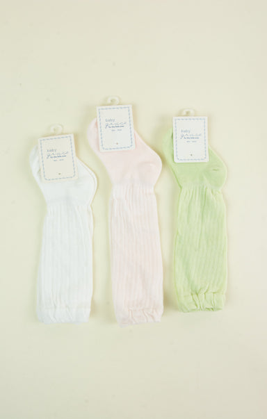 Three pairs of pastel-colored ribbed tank tops on a light beige background