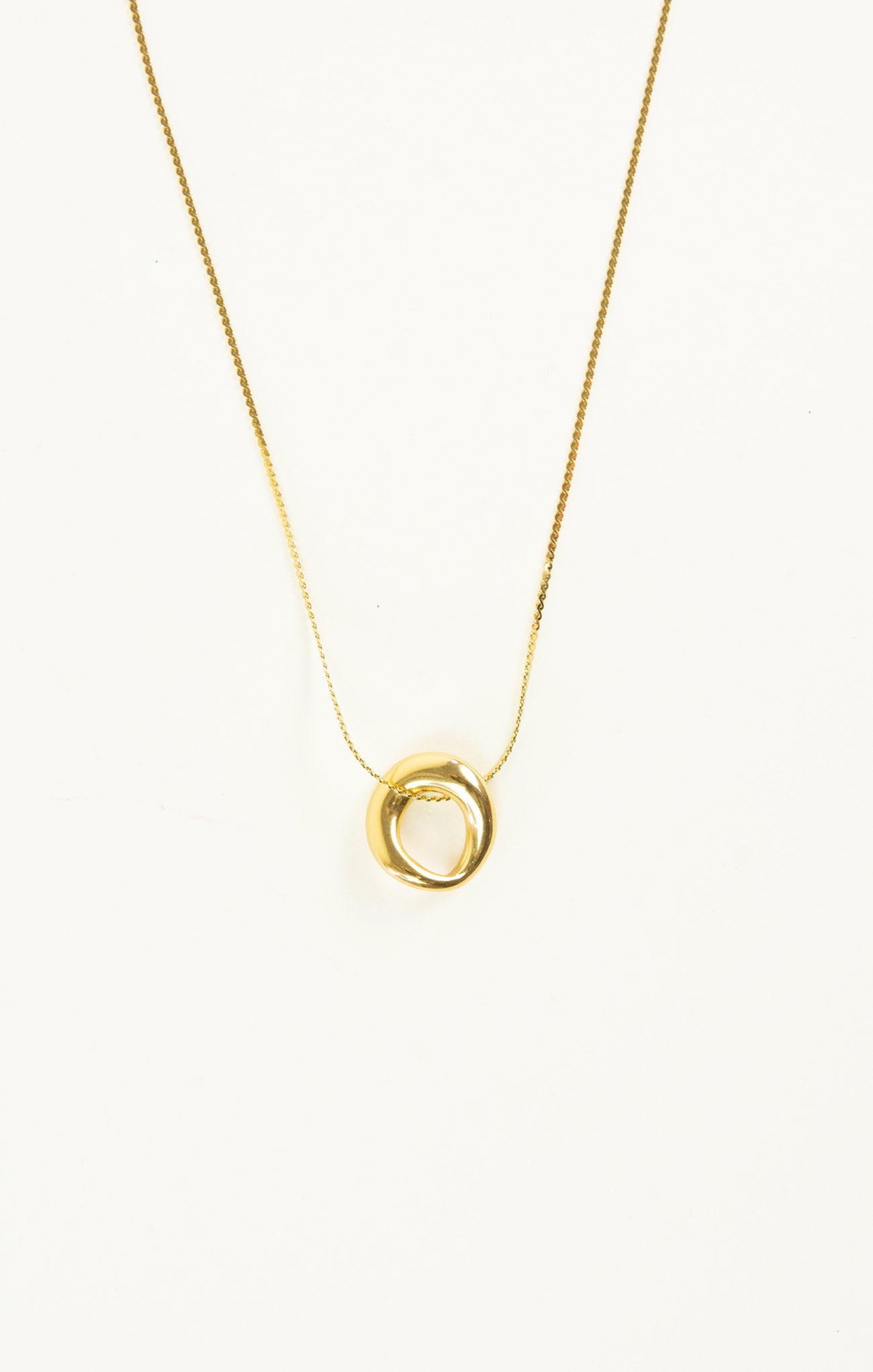 Gold necklace with a circular pendant on a white background