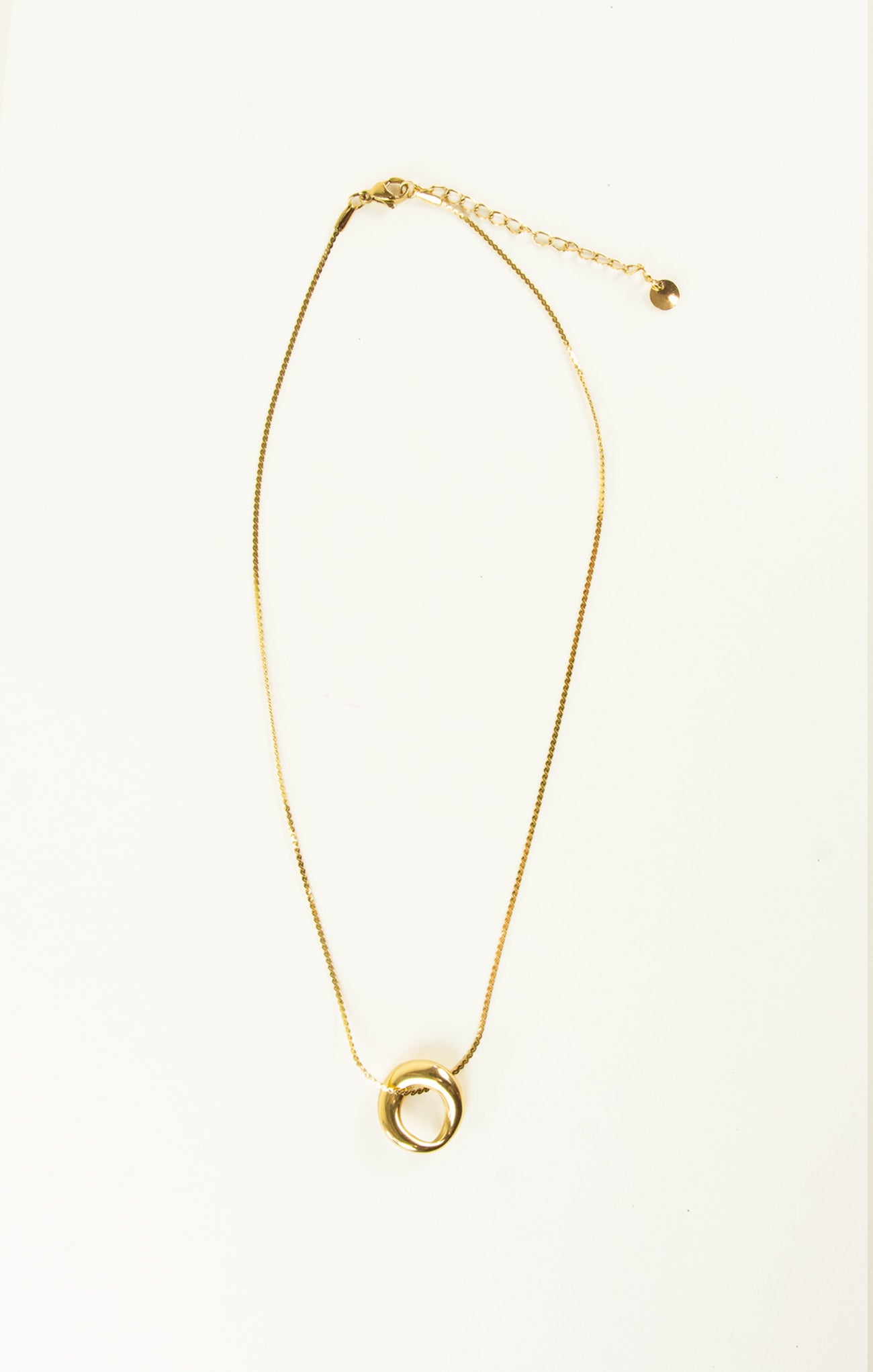 Gold necklace with a circular pendant on a white background