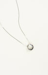 Silver necklace with a circular pendant on a white background