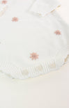 White knitted fabric with pink floral embellishments on a light pink background