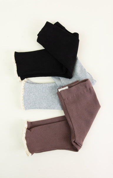 Three pairs of leggings in black, blue, and brown on a white background