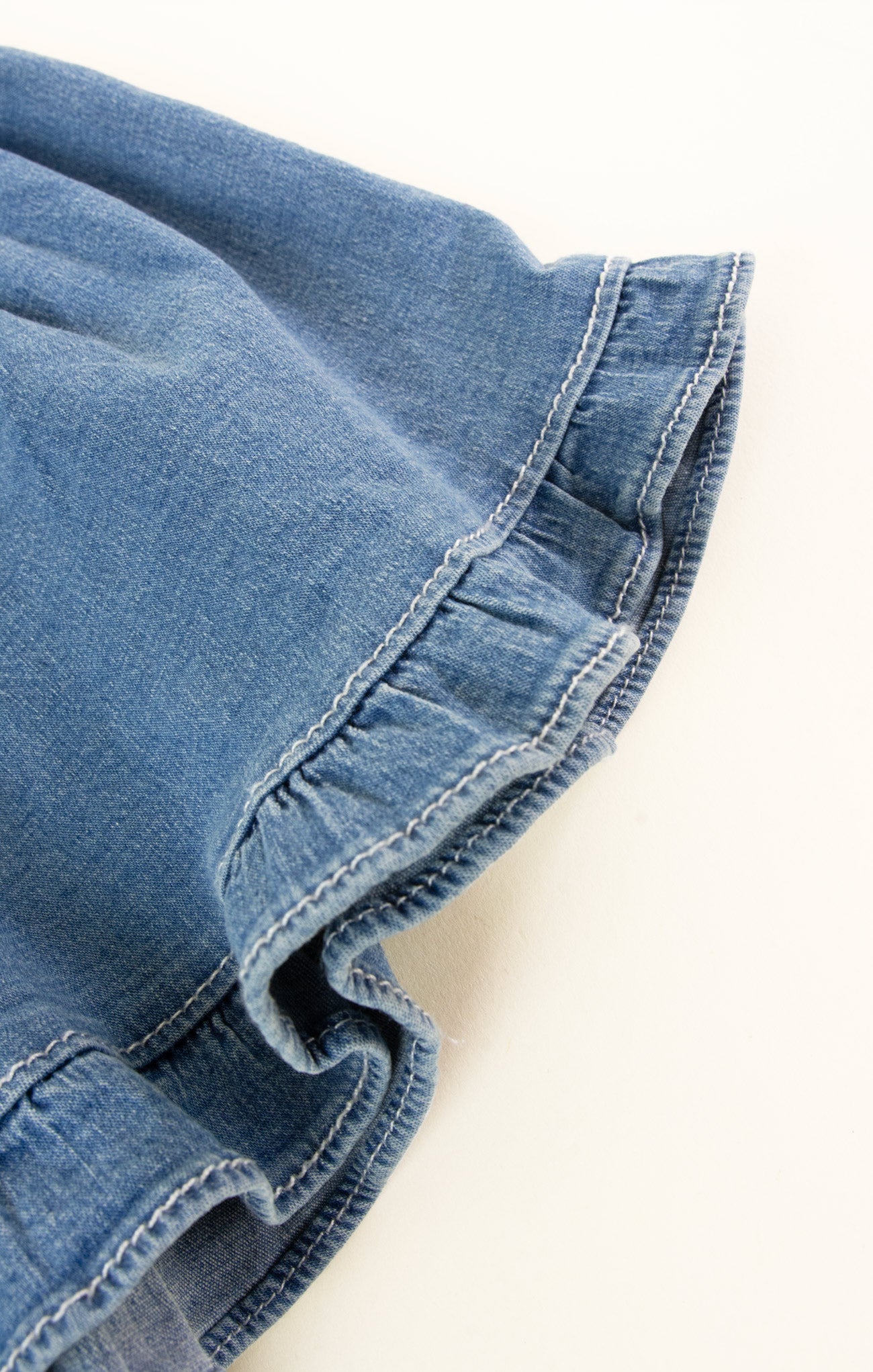 Close-up of blue denim fabric with frayed edge on a white background