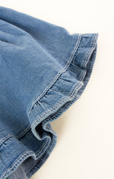 Close-up of blue denim fabric with frayed edge on a white background