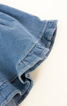Close-up of blue denim fabric with frayed edge on a white background