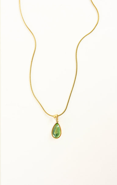 Gold necklace with a green teardrop pendant on a white background