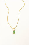 Gold necklace with a green teardrop pendant on a white background