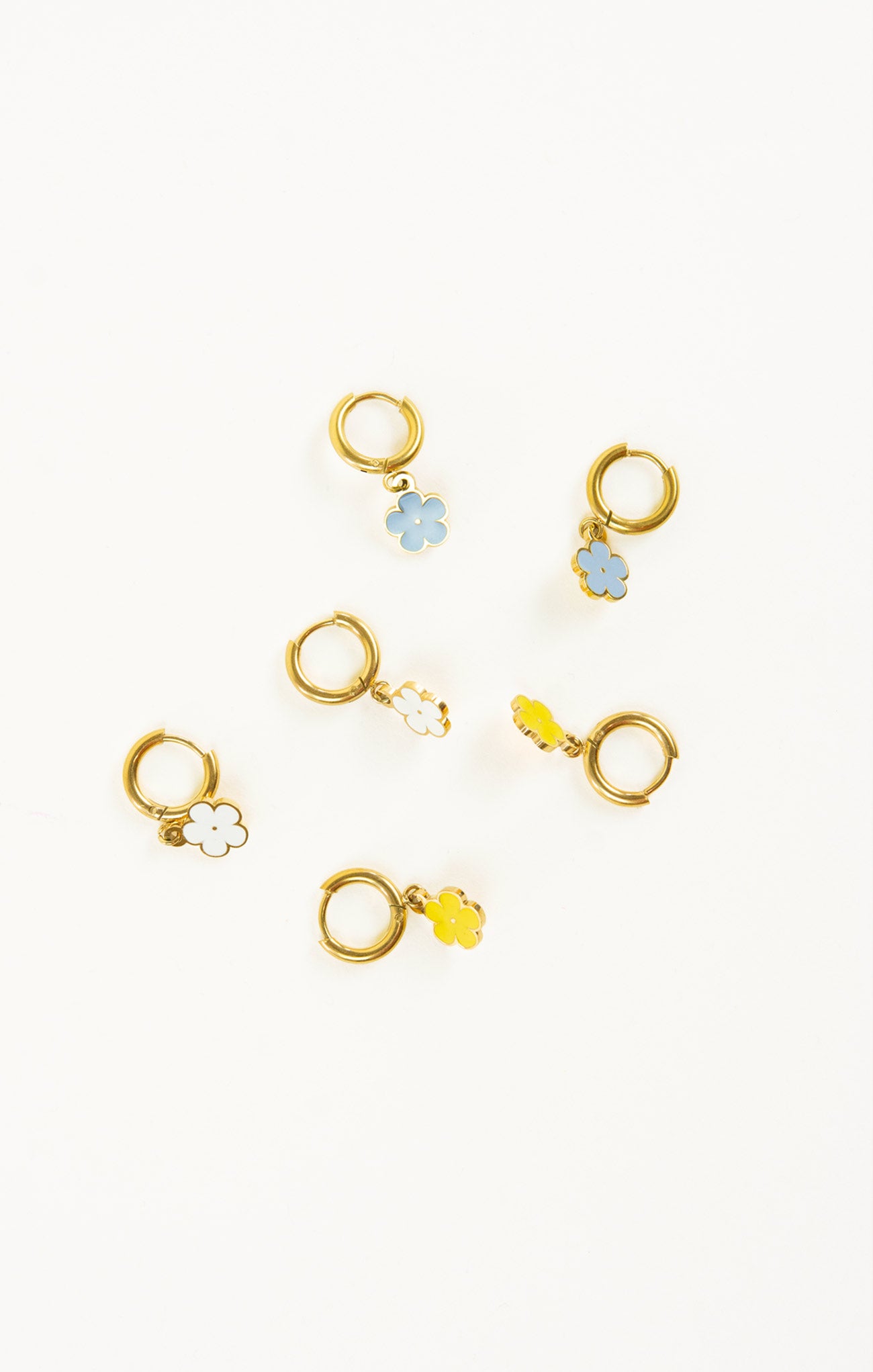 Set of gold earrings with floral designs on a white background