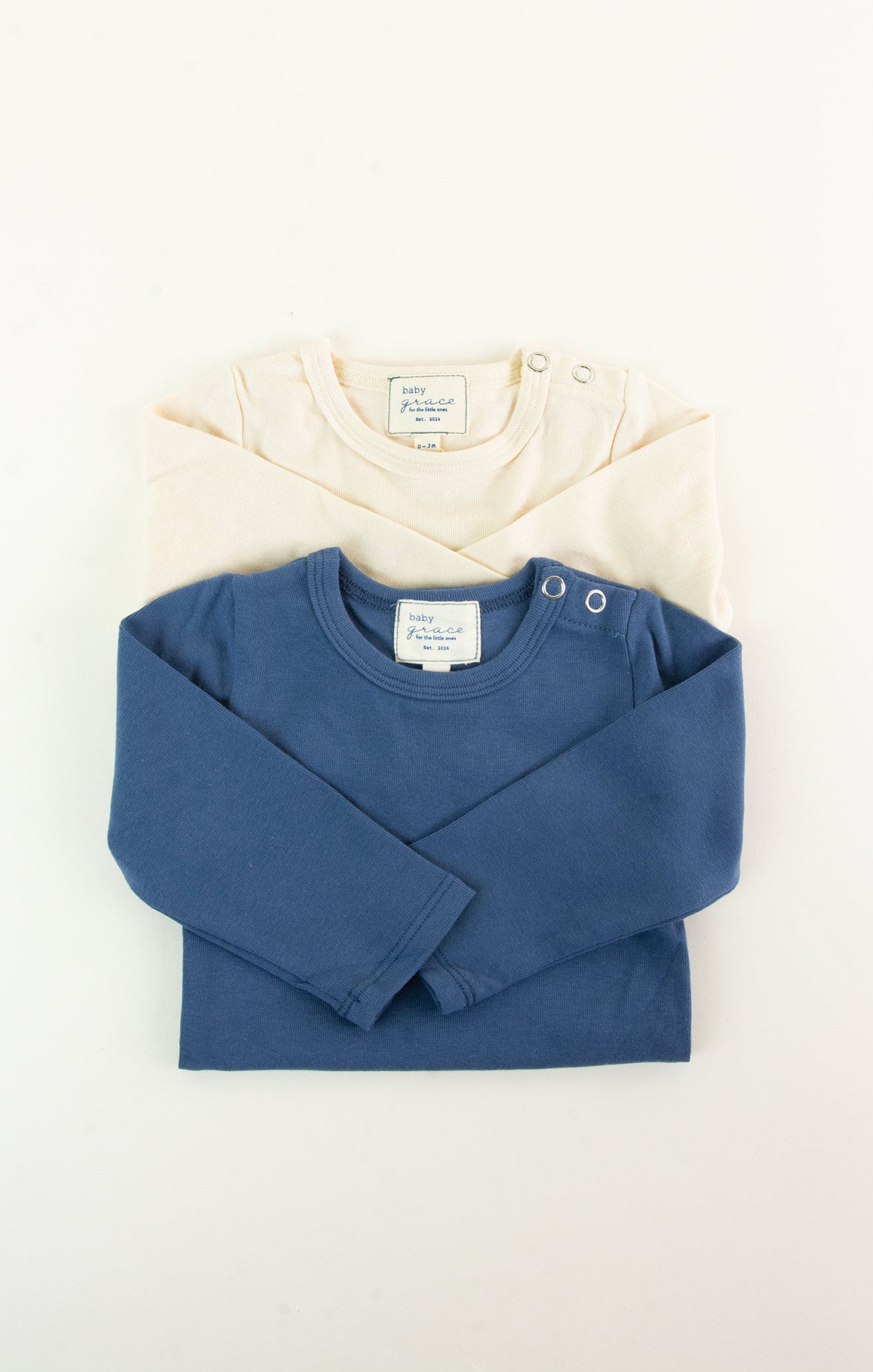 Blue long-sleeve shirt and cream sweater on a white background