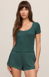 Woman wearing a green romper against a beige background