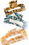 Set of three hair clips with leopard print, blue and white marble, and orange and white pattern on a white background.
