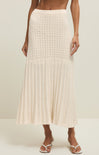 Person wearing a beige crochet skirt on a plain background