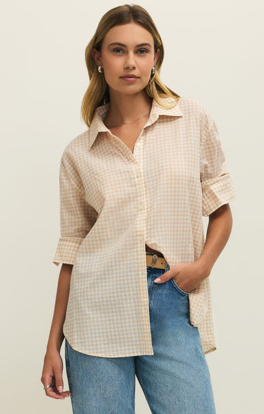 Woman wearing a checkered shirt and jeans on a plain background
