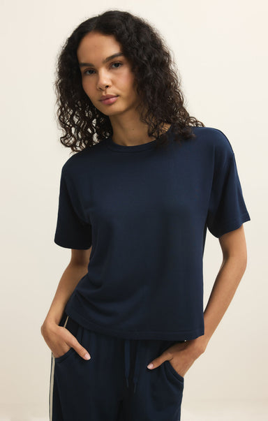 Woman wearing a navy blue t-shirt and pants against a beige background