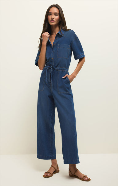 Woman wearing a blue denim jumpsuit on a white background