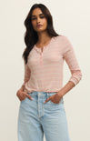 Woman wearing a pink striped long-sleeve top and light blue jeans against a beige background